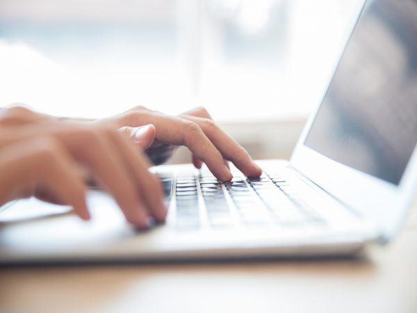 Close-up of male hands typing on laptop keyboard Privé : Gérer mes avis clients